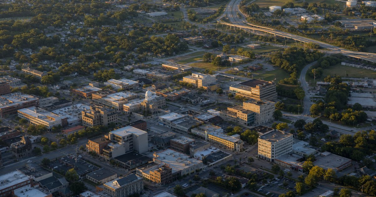 Aerial view of a mid-sized American town with a downtown main street, residential blocks and a highway interchange, late afternoon light